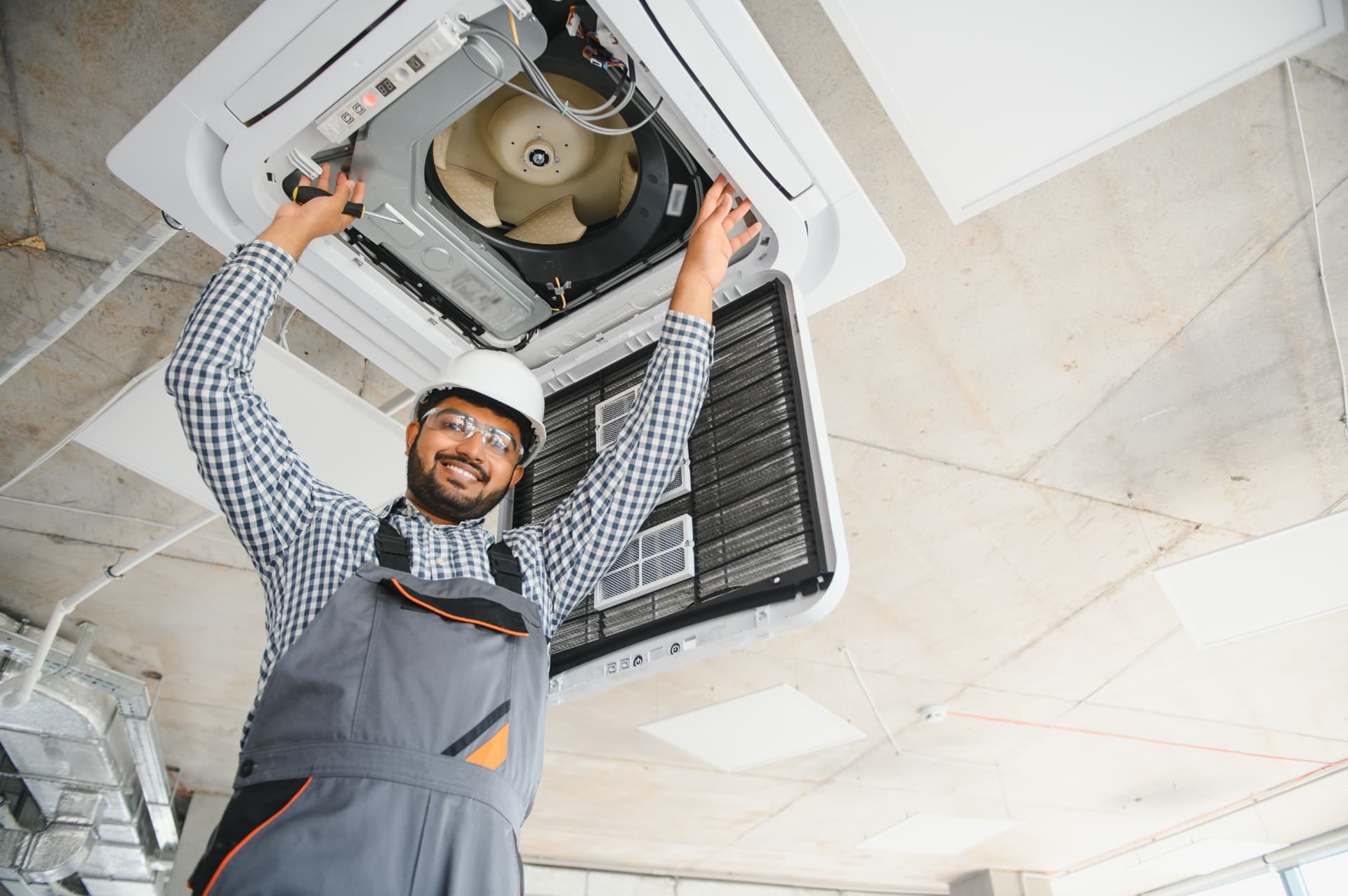 HVAC technician servicing a ceiling-mounted cassette air conditioning unit